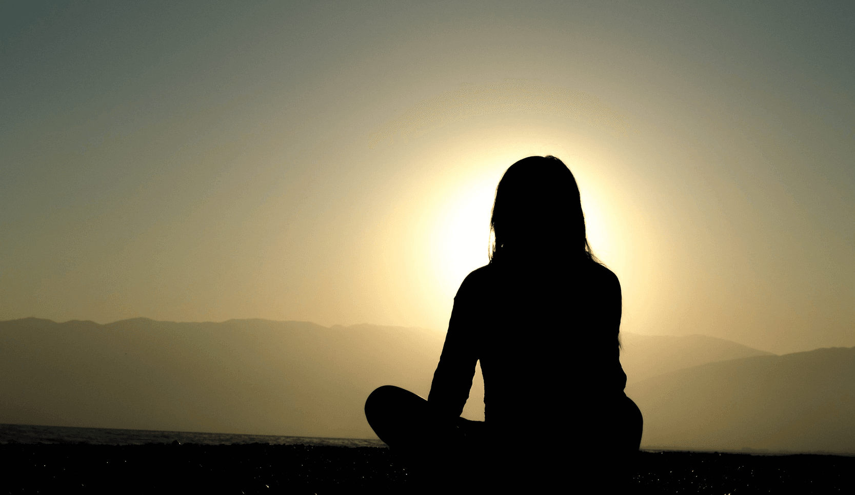Silhouette of a person meditating at sunset